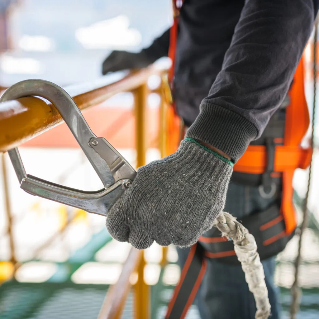 Main gantée tenant une pince près d’une corde
